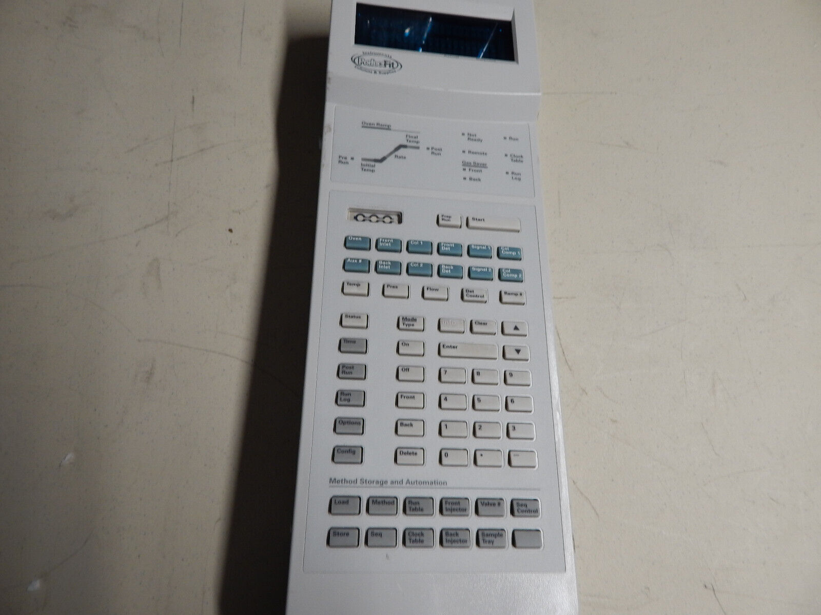 A white electronic device with a screen and many buttons.