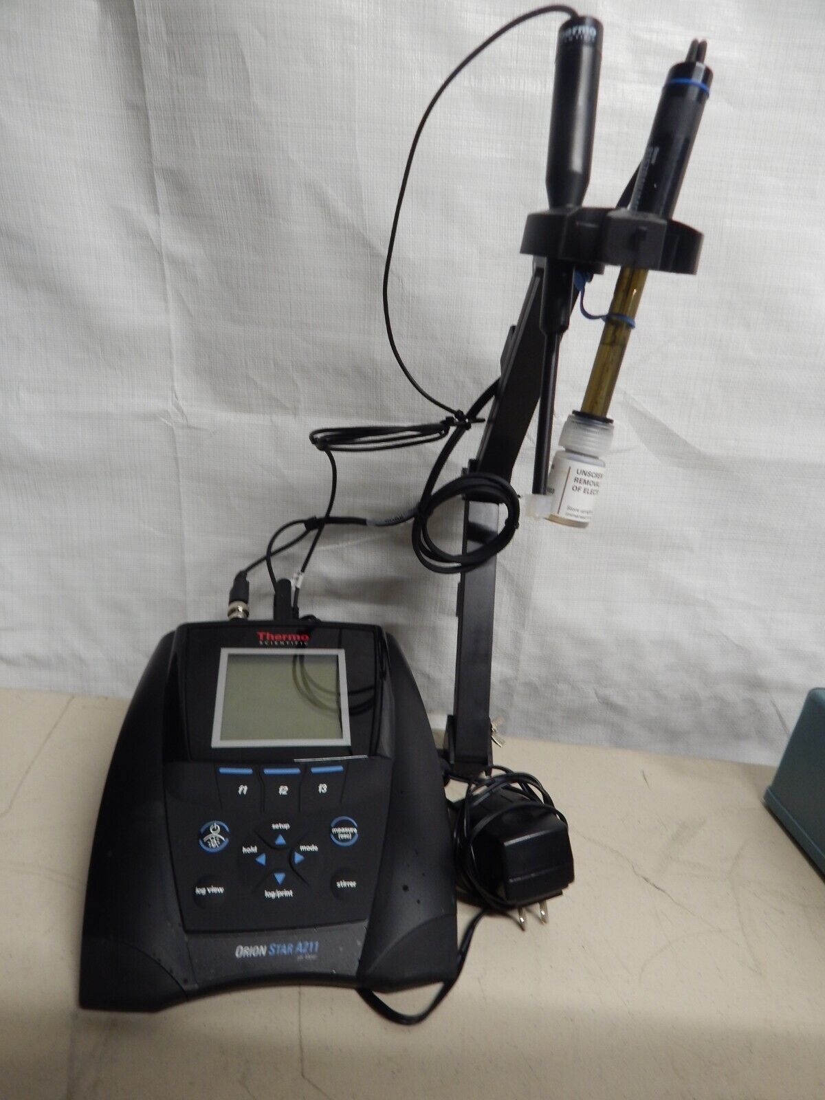 A benchtop pH meter with a probe and a power adapter.