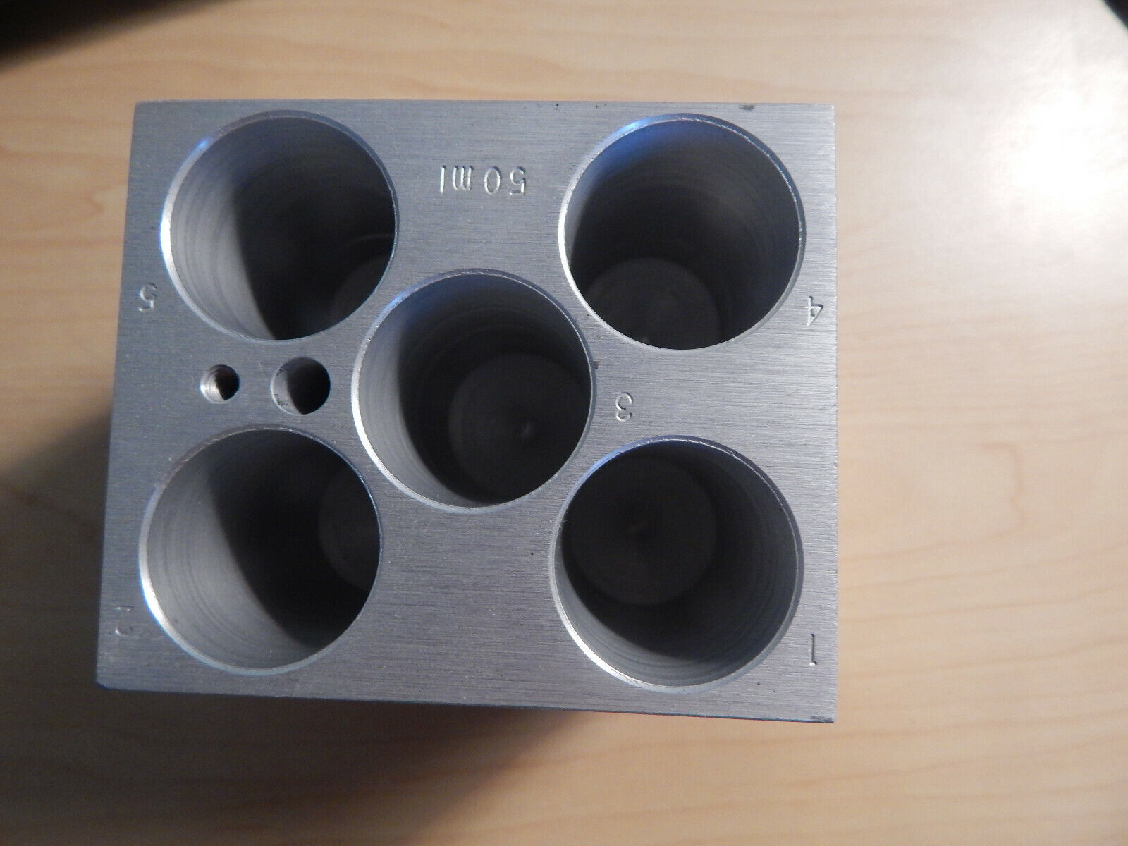 A metal block with five holes.